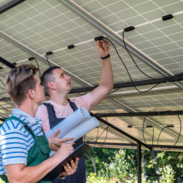 Two young men electrician checking solar system on the station